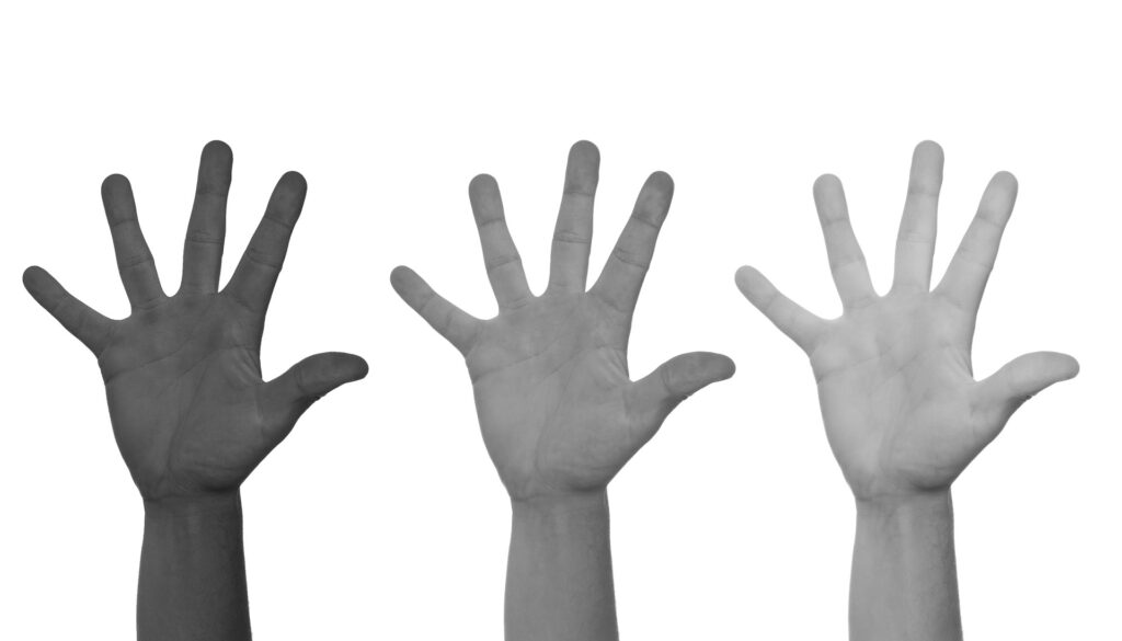 Tre händer med olika hudfärg sträcks upp i luften.